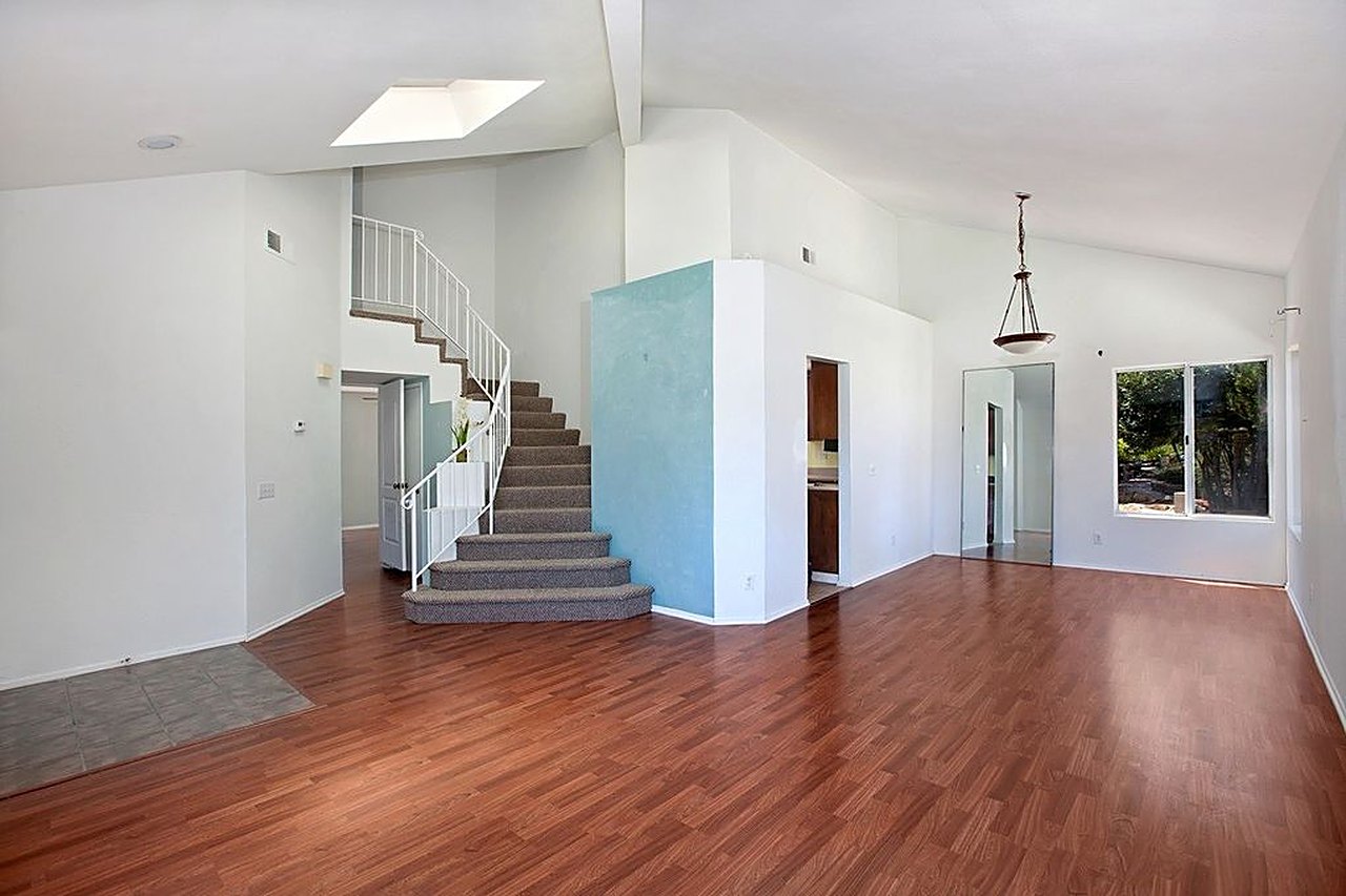 Living room before: dated railing, worn flooring, flat lighting