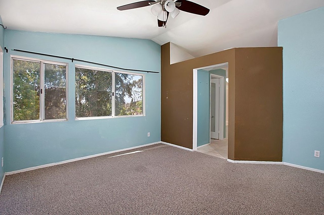 Bedroom before: dated colors, worn carpet, boxed-in bathroom entry